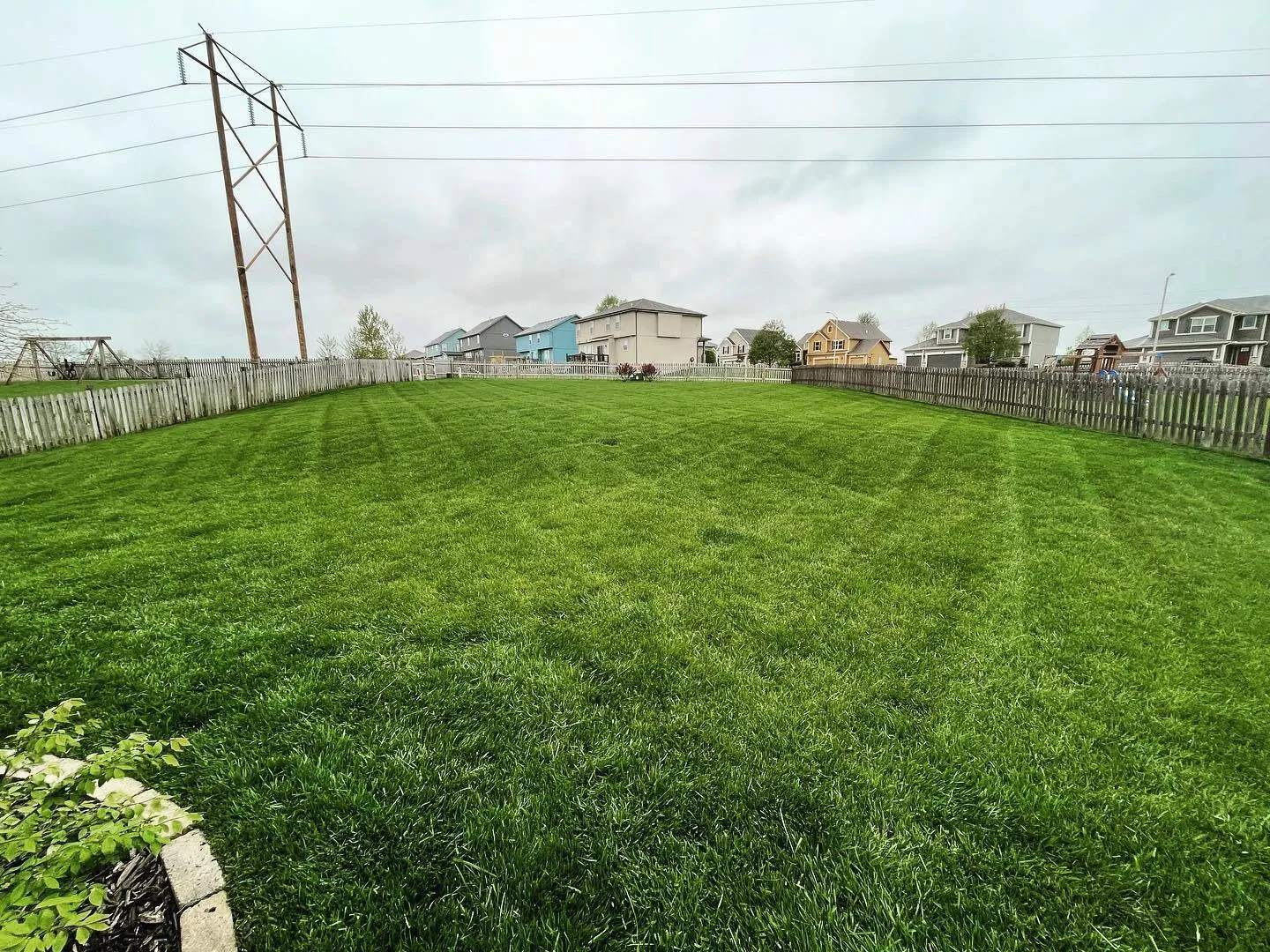 Fenced backyard with striped lawn in Liberty, MO area