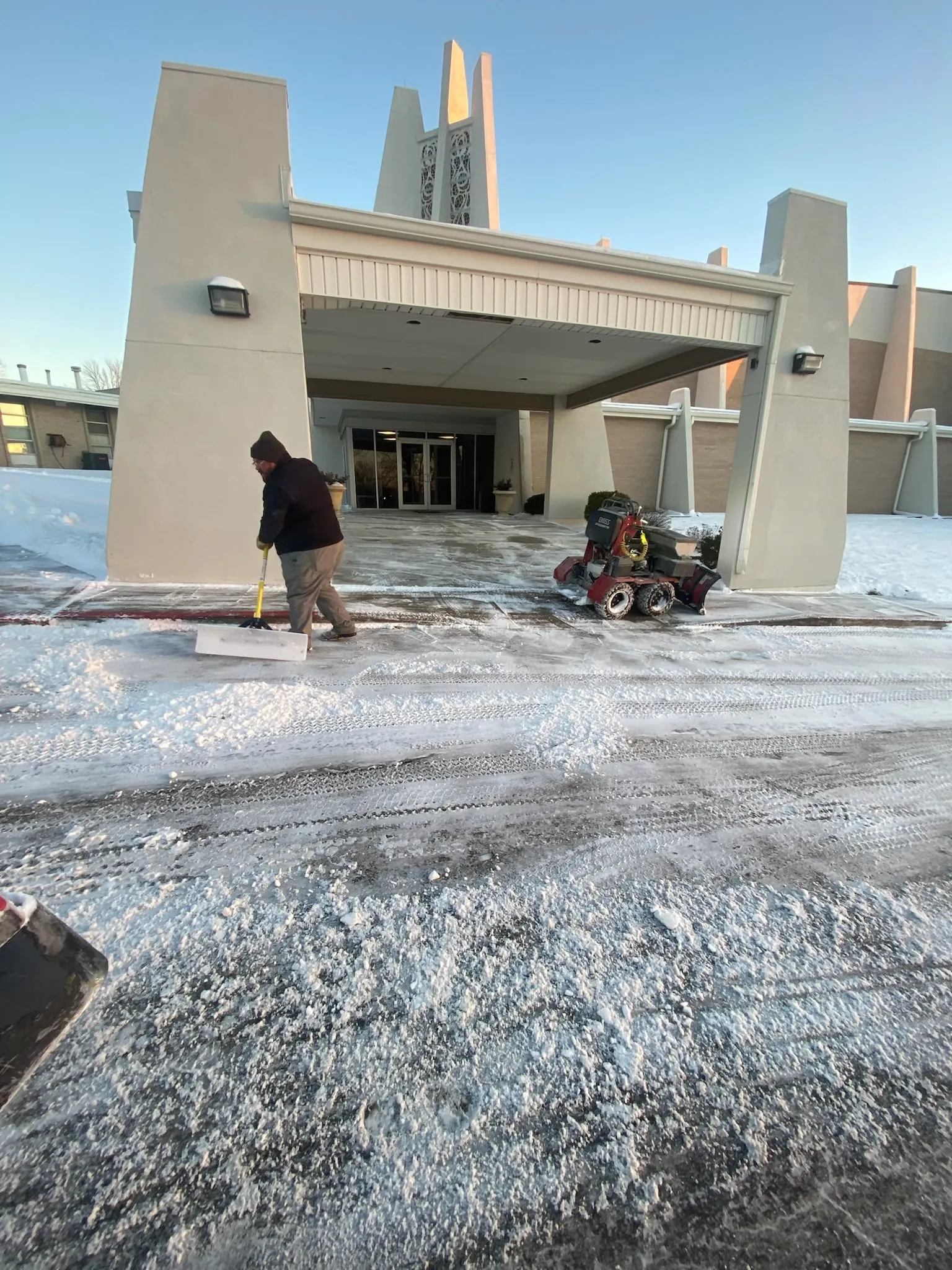 Crew clearing walkways at a KC Northland church campus under a clear blue sky