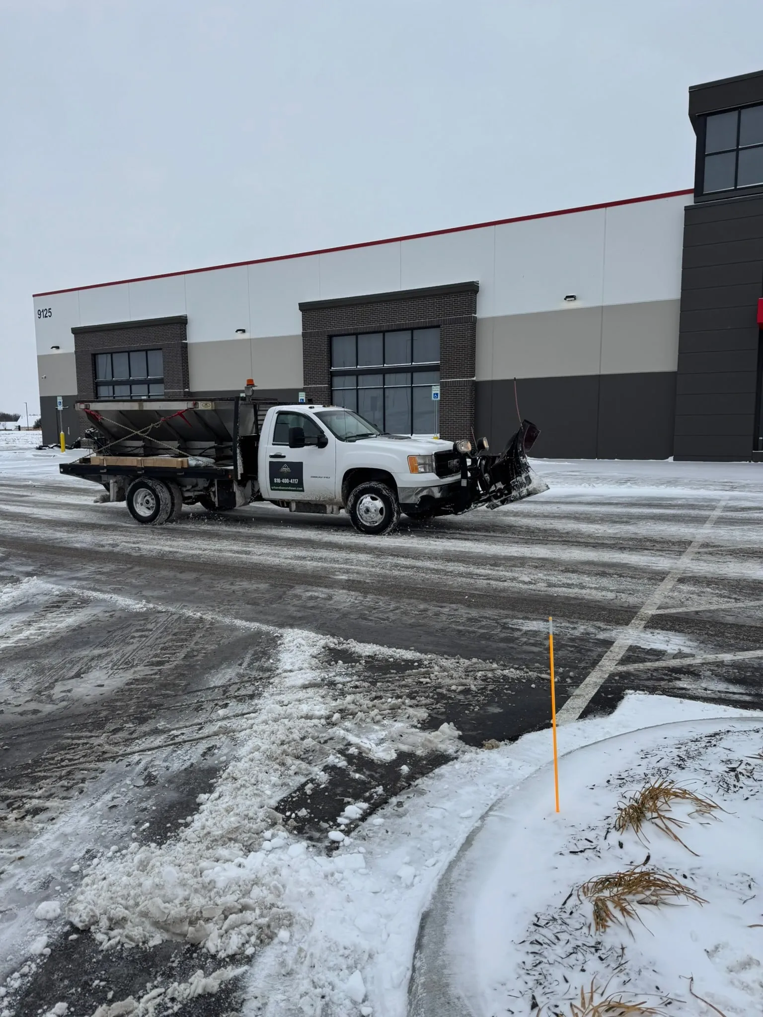 Branded Urban Diamond plow truck and salt spreader trailer servicing a commercial parking lot