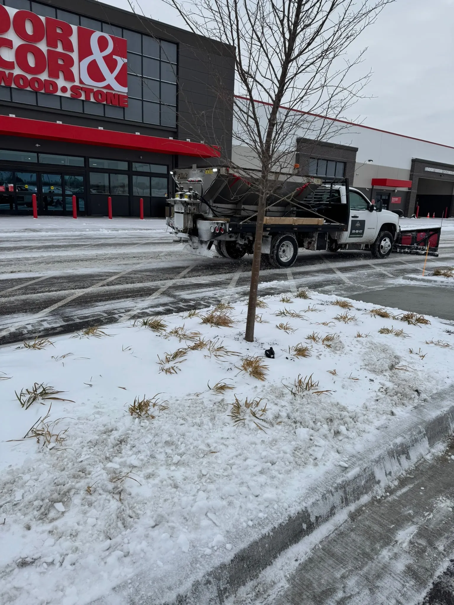 Salt spreader truck treating a commercial parking lot